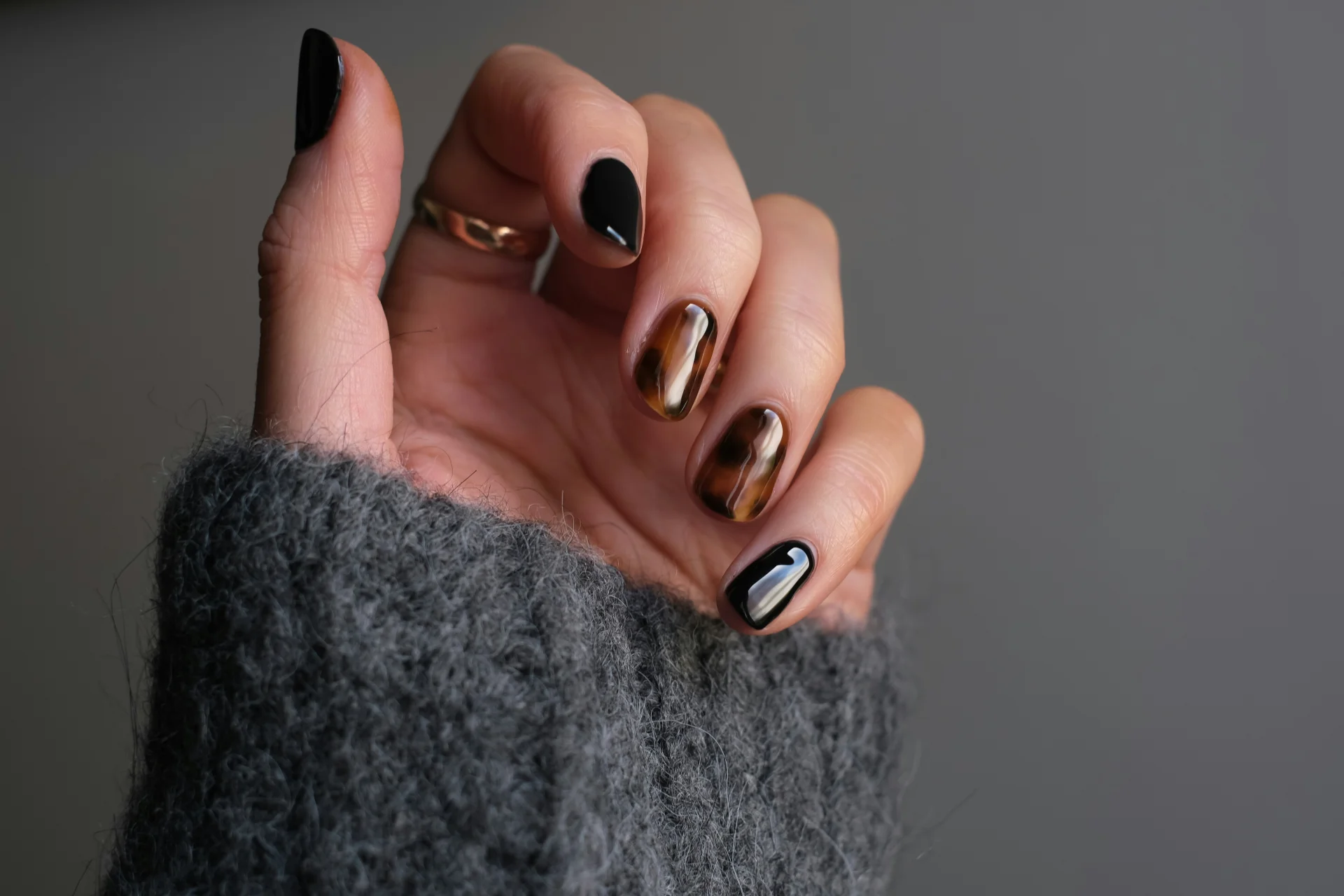 Osoba nosząca srebrny pierścionek z czarnym manicure, dłoń z zadbanymi paznokciami.