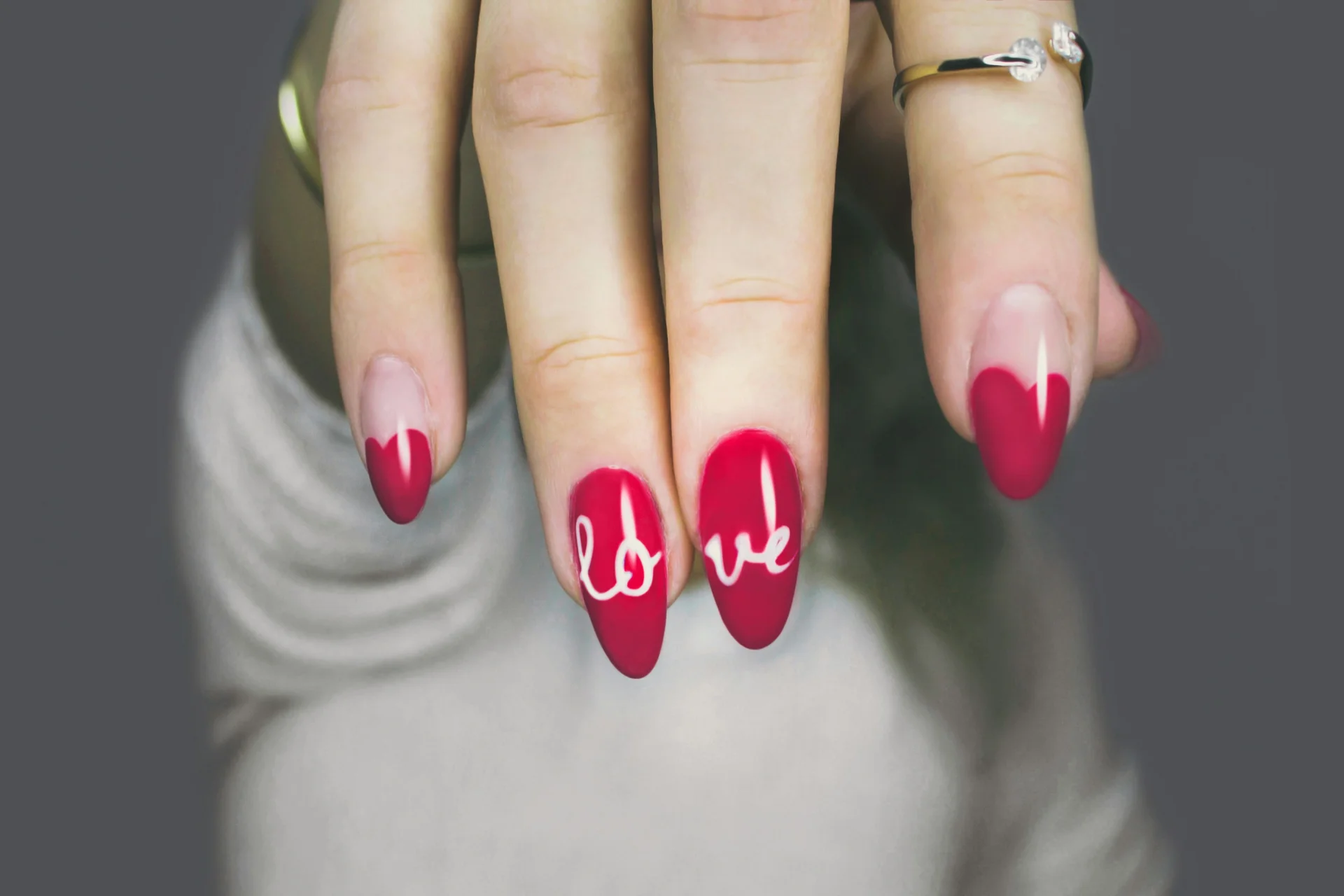 Zbliżenie na dłoń kobiety z różowym manicure hybrydowym, paznokcie pomalowane starannie.